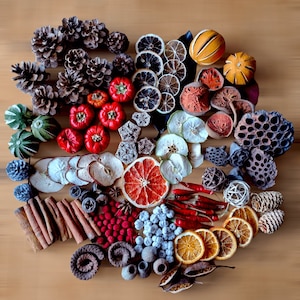 Puede incluir: Una variedad de frutas secas, especias y otros elementos naturales dispuestos en forma de corazón sobre una superficie de madera. Los artículos incluyen naranjas secas, manzanas, piñas, palitos de canela y pimientos rojos. El texto "Fluff & Co" está escrito en blanco en la parte inferior de la imagen.