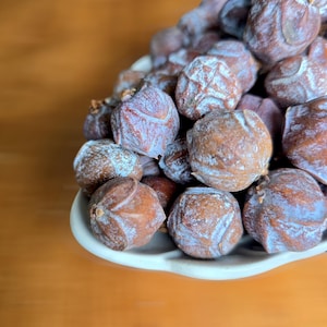 Puede incluir: Un cuenco de cerámica blanca lleno de un montón de fruta seca marrón y gris.