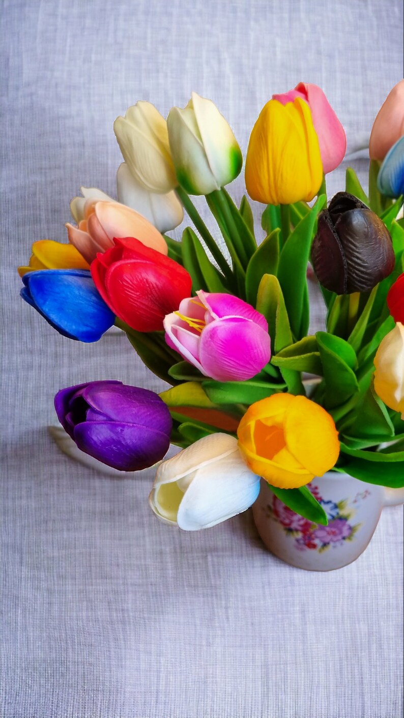 Peut inclure: Un bouquet de tulipes color&eacute;es dans un vase &agrave; motif floral. Les tulipes sont dans des tons de bleu, violet, rose, rouge, jaune, blanc et noir.