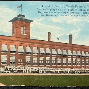 May include: A brick building with a large sign that reads "The 20th Century Tooth Factory. York, Pa. Dentists Supply Co's. New Factory with its 1000 Employees. The largest manufactory of Artificial Teeth in the World. Cor. Grantley Street and College Avenue, York, Pa."