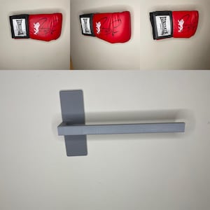 May include: A grey metal wall-mounted towel rack with a horizontal bar. The rack is mounted to a white wall.
