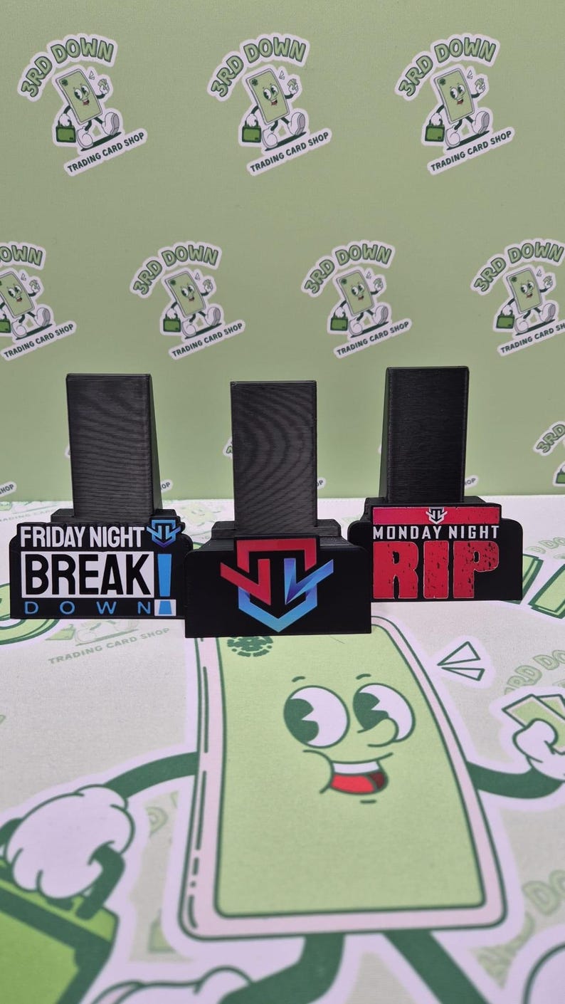 May include: Three black acrylic display stands with different designs. The first stand has a black and white graphic of a video game character with the text "Friday Night Break Down". The second stand has a blue, red, and white graphic of a video game character. The third stand has a red and white graphic of a video game character with the text "Monday Night Rip".