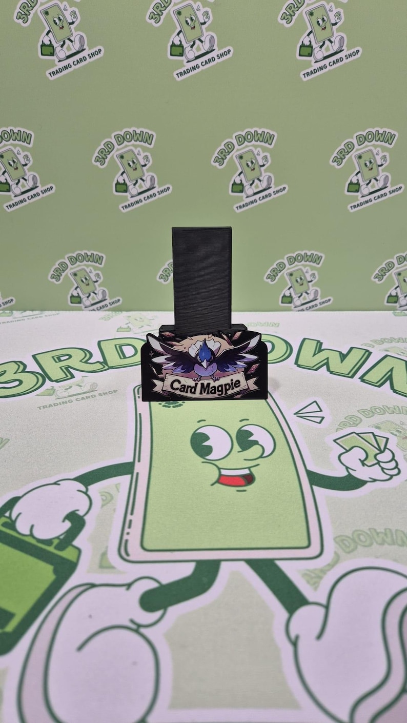 May include: A black wooden stand with a colorful graphic of a bird with the text "Card Magpie" on it.