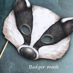 May include: A black and white badger mask with a stick attached to the back. The mask has a white snout and black eyes. The text "Badger mask" is printed below the mask.