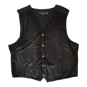 Può includere: Un gilet in velluto nero con scollo a V e chiusura frontale a cinque bottoni rotondi. L'etichetta interna riporta la scritta Jay Jacobs. Il capo presenta un design senza maniche con un orlo a punta nella parte centrale anteriore.