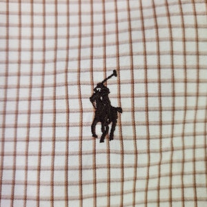 May include: A brown and white checkered fabric with a black embroidered polo player logo.