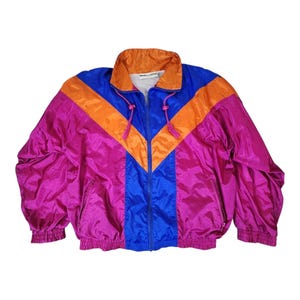 May include: A long-sleeve windbreaker jacket featuring a vibrant color-blocked design in magenta, bright blue, and orange. The jacket has a high collar, a full-length front zipper, two side pockets with zippers, and elasticized cuffs and hem.