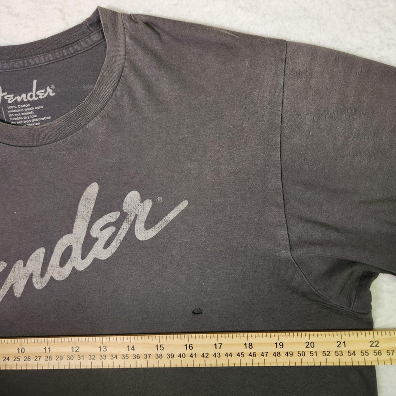 Puede incluir: Camiseta Fender gris oscuro con el logo Fender en blanco. La camiseta es 100% algod&oacute;n y tiene cuello redondo. La camiseta es talla L.