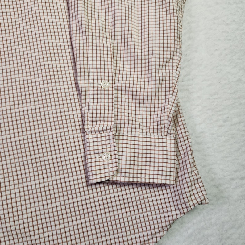 May include: A white and brown checkered long-sleeve shirt with a button cuff.