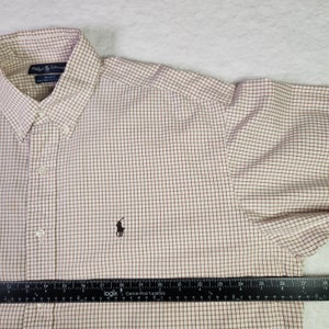 May include: A white and brown plaid long-sleeve button-down shirt with a small embroidered polo player logo on the left chest. The shirt has a standard collar and a button-up front.