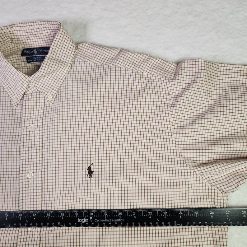 May include: A white and brown plaid long-sleeve button-down shirt with a small embroidered polo player logo on the left chest. The shirt has a standard collar and a button-up front.