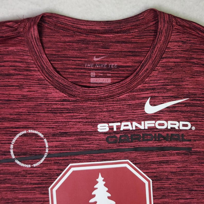 Puede incluir: Camiseta deportiva DRI-FIT granate y negra. La camiseta presenta el logo de Nike y el texto "STANFORD CARDINAL". Un gr&aacute;fico blanco de un &aacute;rbol es visible en la camiseta.