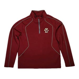 May include: A maroon long-sleeve athletic shirt with a quarter-zip neckline. The shirt features gray accent lines and a small logo on the chest. The overall design is simple and sporty, suitable for athletic activities or casual wear.