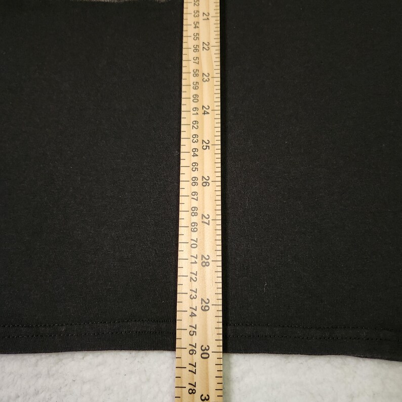 Puede incluir: Primer plano de una tela negra con una regla amarilla que mide de 53 a 78 cm. La regla tiene marcas para cada cent&iacute;metro e incrementos m&aacute;s peque&ntilde;os. La tela parece ser de un color s&oacute;lido.