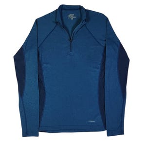 May include: A blue long-sleeve pullover with a quarter-zip neckline and a stand-up collar. The garment features darker blue side panels and raglan sleeves. The Patagonia brand logo is printed in white on the lower front left side.