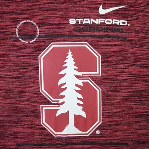 Puede incluir: Camiseta deportiva granate con el logo de Stanford Cardinal. El logo presenta un &aacute;rbol blanco dentro de una "S" roja. El logo de Nike es visible encima del texto "STANFORD. CARDINAL". Las palabras "HOME OF CHAMPIONS" est&aacute;n impresas en un c&iacute;rculo.