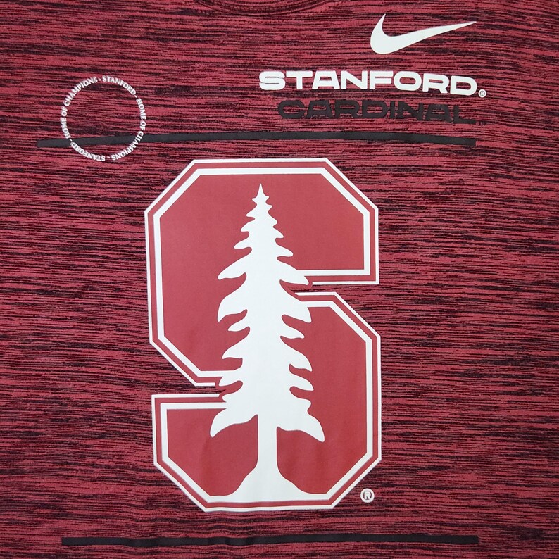Puede incluir: Camiseta deportiva granate con el logo de Stanford Cardinal. El logo presenta un &aacute;rbol blanco dentro de una "S" roja. El logo de Nike es visible encima del texto "STANFORD. CARDINAL". Las palabras "HOME OF CHAMPIONS" est&aacute;n impresas en un c&iacute;rculo.