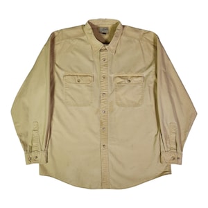 Op de afbeelding: Een overhemd met lange mouwen en knoopsluiting in een effen beige kleur. Het overhemd heeft een puntige kraag, een knoopsluiting aan de voorzijde en twee borstzakken met knoopkleppen. De manchetten zijn ook voorzien van knopen en het L.L. Bean label is zichtbaar.