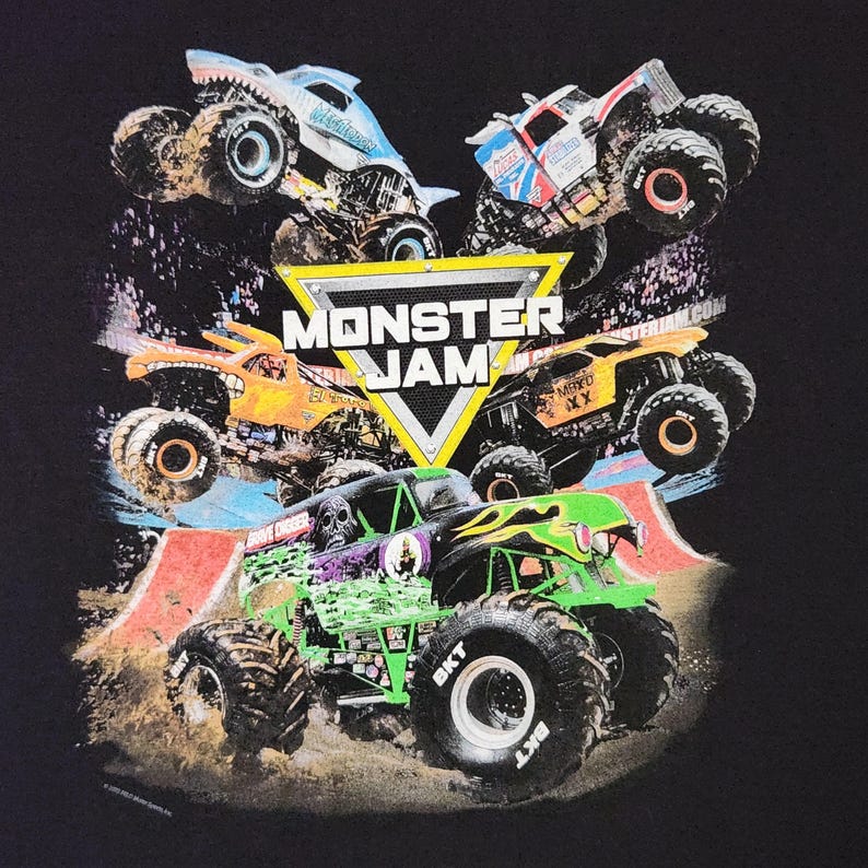 Puede incluir: Camiseta negra con un dise&ntilde;o de varios monster trucks en acci&oacute;n, incluido el Grave Digger. El dise&ntilde;o presenta el logotipo de Monster Jam en un tri&aacute;ngulo amarillo, con camiones de varios colores.