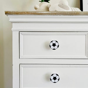 May include: White dresser with two drawers and football shaped drawer pulls.