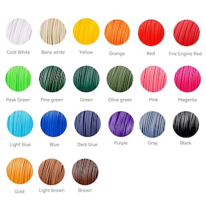 Op de afbeelding: Een kleurenkaart met 18 verschillende kleuren filament voor 3D-printen. De kleuren omvatten koud wit, botwit, geel, oranje, rood, brandweer rood, piek groen, dennen groen, groen, olijfgroen, roze, magenta, lichtblauw, blauw, donkerblauw, paars, grijs, zwart, goud, lichtbruin en bruin.