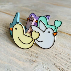 May include: A set of four colorful bird-shaped figurines. The birds are made of plastic and have a cartoonish style. The birds are yellow, blue, purple, and green.