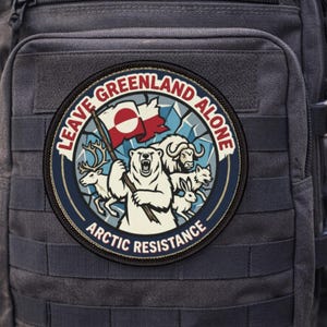Puede incluir: Un parche redondo con el texto "LEAVE GREENLAND ALONE" y "ARCTIC RESISTANCE". El parche presenta un oso polar sosteniendo una bandera, con otros animales árticos y una bandera de Groenlandia. El parche está sobre una mochila negra.