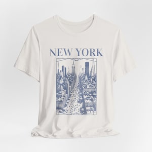 May include: White t-shirt with a blue graphic print of the New York City skyline and the text "NEW YORK" above the image.