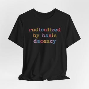 Könnte beinhalten: Schwarzes T-Shirt mit dem Text "radicalized by basic decency" in bunten Buchstaben.