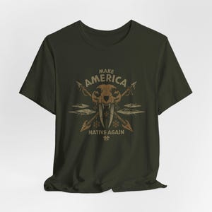 May include: A dark green t-shirt with a graphic design featuring a stylized animal skull with fangs and crossed arrows. The text "Make America Native Again" is printed below the skull.