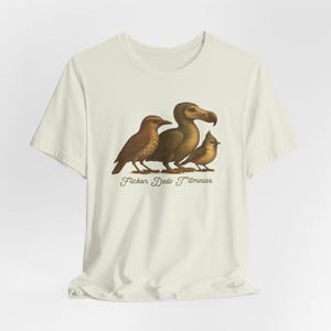 May include: A white t-shirt with a brown, green, and blue illustration of a bird, a dodo, and a titmouse. The text "Flicker Dodo Titmouse" is printed below the illustration.