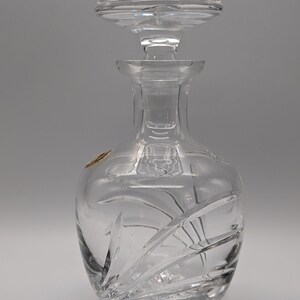 May include: A clear glass decanter with a cut glass design. The decanter has a stopper with a cut glass design.