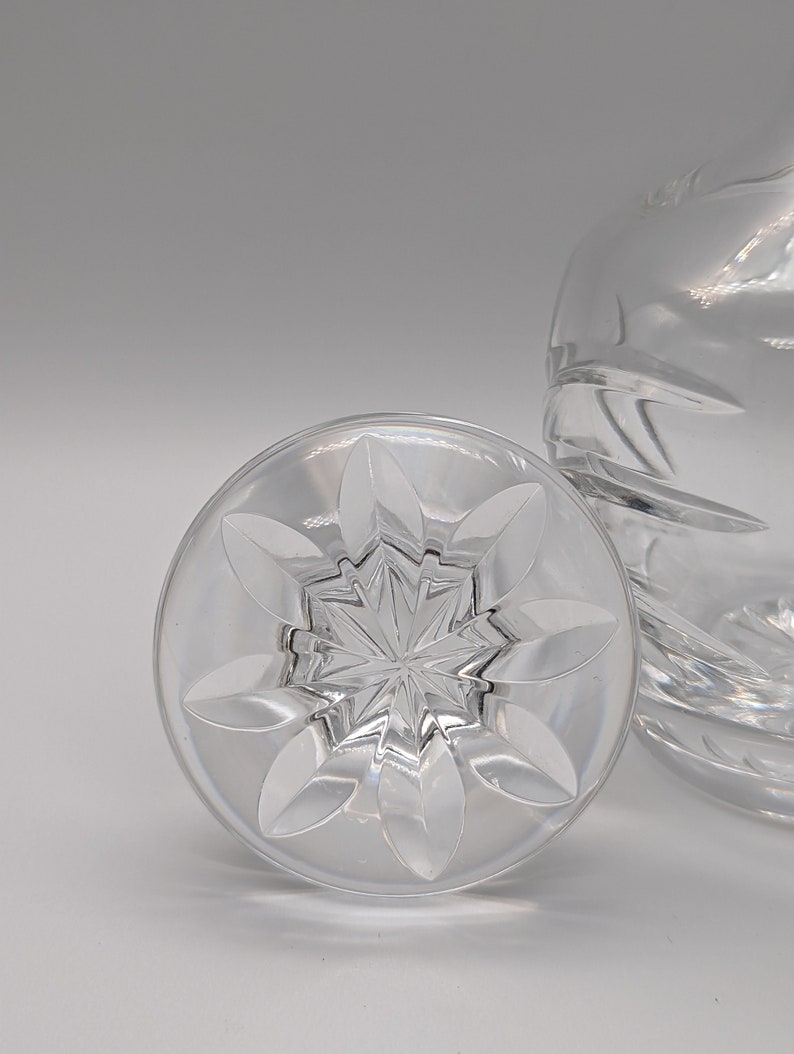 May include: A clear glass bottle stopper with a starburst design and a flower-shaped rim.