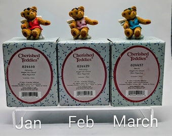 May include: Three "Cherished Teddies" figurines, each a teddy bear angel on a cloud, in red, pink, and blue outfits. The boxes below are labeled "January", "February", and "March".