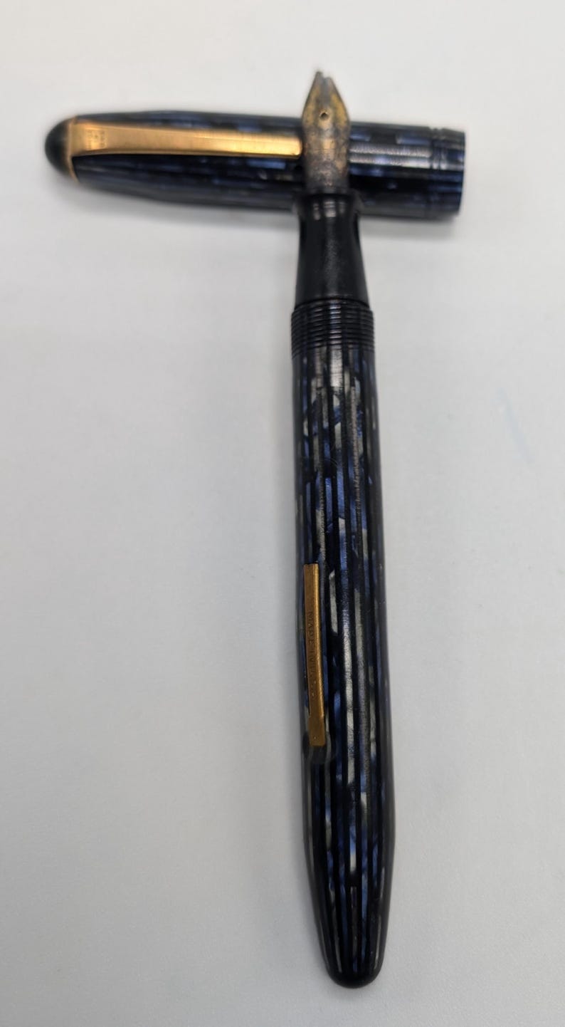 May include: A blue and silver striped fountain pen with a gold trim and a black cap.