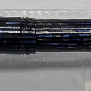 May include: A blue and gold fountain pen with a striped pattern and the words "MADE IN USA" on the side.
