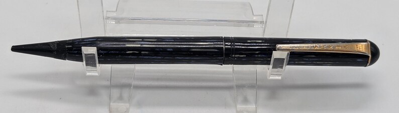 May include: A black and gold mechanical pencil with a textured barrel and the inscription "WATERMAN" on the side.