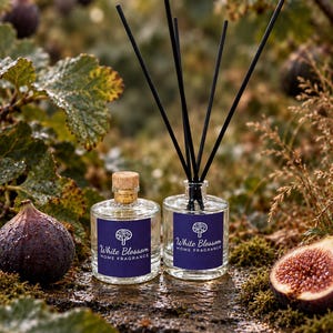 May include: Two clear glass bottles with blue labels reading White Blossom Home Fragrance. One bottle has a cork stopper, and the other contains five black reed diffuser sticks. The labels feature a white tree icon and text.