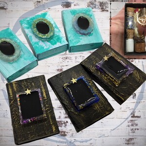 May include: An assortment of decorative boxes in various colors, including teal and gold, with resin embellishments. Some boxes feature a star-shaped accent. A small box filled with vials, feathers, and other items is also present.