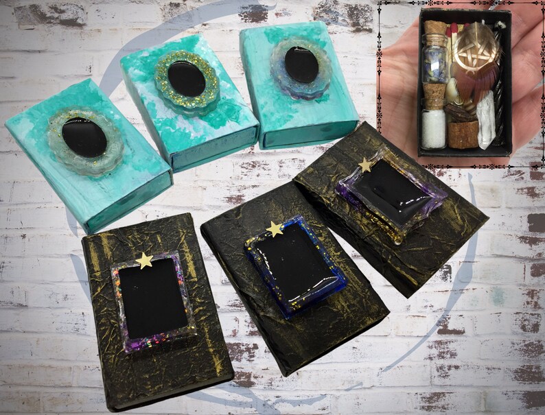 May include: An assortment of decorative boxes in various colors, including teal and gold, with resin embellishments. Some boxes feature a star-shaped accent. A small box filled with vials, feathers, and other items is also present.