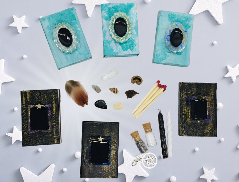 May include: An assortment of mystical items, including small, decorated books, feathers, shells, crystals, matches, candles, and bottles with corks. The books are teal and black, with decorative embellishments. The items are arranged on a light gray surface with white star decorations.