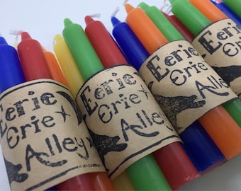 May include: A set of colorful candles wrapped in brown paper with the text "Eerie Erie Alley" printed on them.
