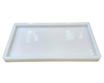 May include: A white rectangular silicone mold with a raised edge. The mold is designed for making resin crafts.