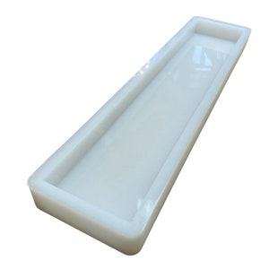 May include: A white rectangular silicone mold for making resin crafts. The mold has a smooth, glossy finish and is designed to create a rectangular tray or dish.