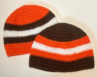 May include: Two crocheted hats with brown, orange, and white stripes. The hats are made with a chunky yarn and have a simple, classic design.