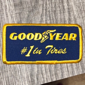 May include: A blue and gold embroidered patch with the text "GOODYEAR #1 in Tires".