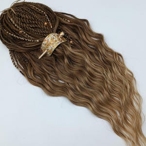 Puede incluir: Extensiones de cabello largas y onduladas, de color marrón y rubio, con un clip para el cabello dorado y blanco. El cabello está peinado en una onda suelta y tiene un aspecto natural.