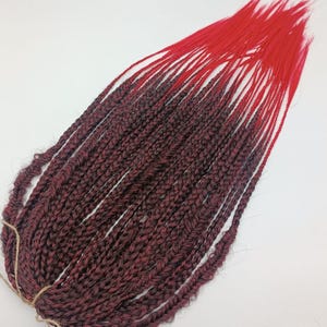 Synthetic black and red braids. Extension of African braids DE and SE. Braids with a free red end. Mix of black and red braids.
