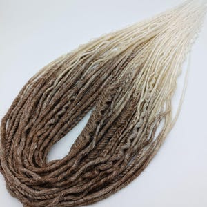 Extension of thin synthetic dreads DE&SE/braids, dreads with ombre effect from medium brown to blonde. Mix of dread textures. Brown dreads