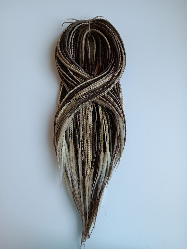 May include: A bundle of brown, blonde, and white synthetic hair extensions. The extensions are braided and tied together at the top.